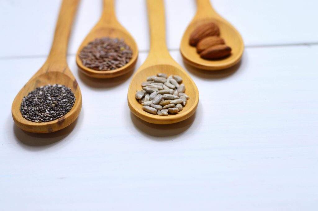 pexels-photo-971080-971080 Close-up of various nuts and seeds in wooden spoons on a white background, showcasing healthy food options.